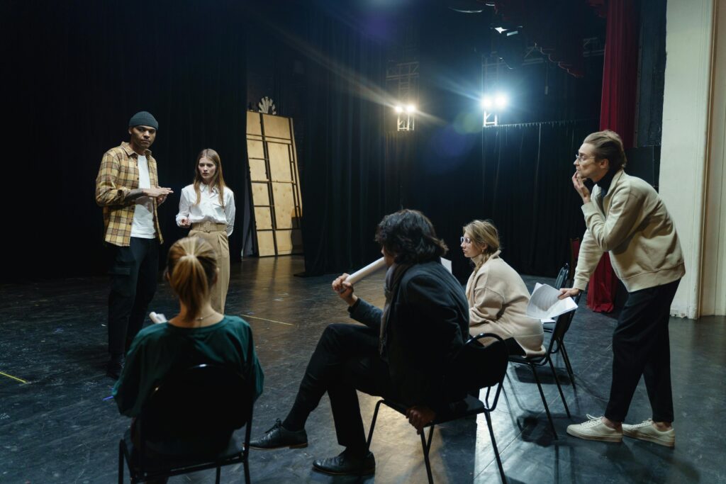 Actors rehearsing on stage with director's guidance in a theater for a live performance.