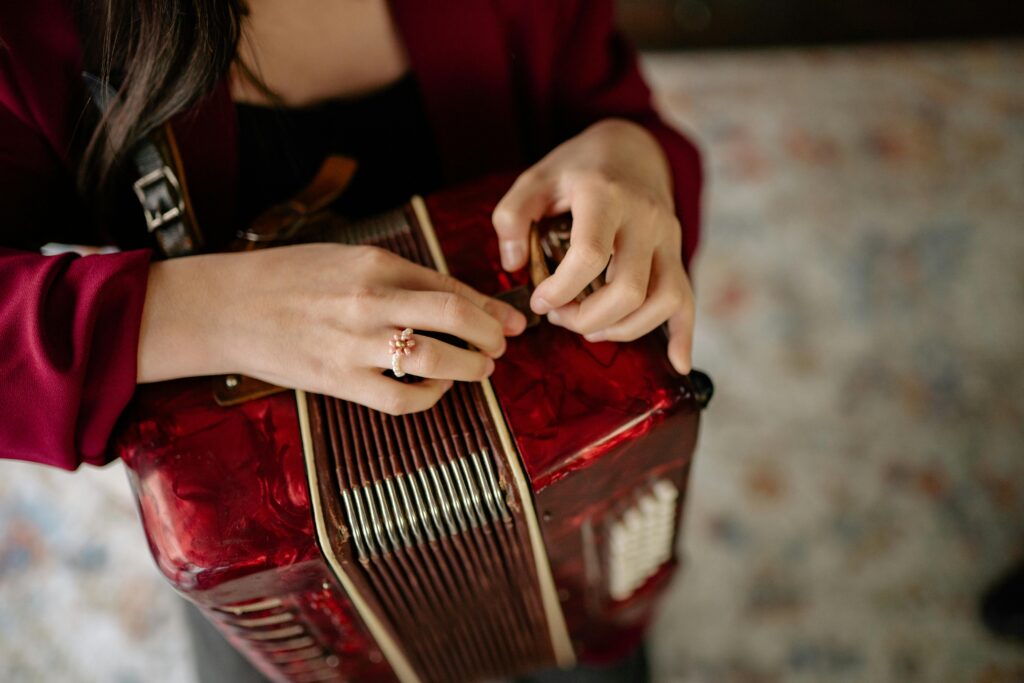 A detailed close-up of a person playing a red accordion, emphasizing the hands and musical instrument.